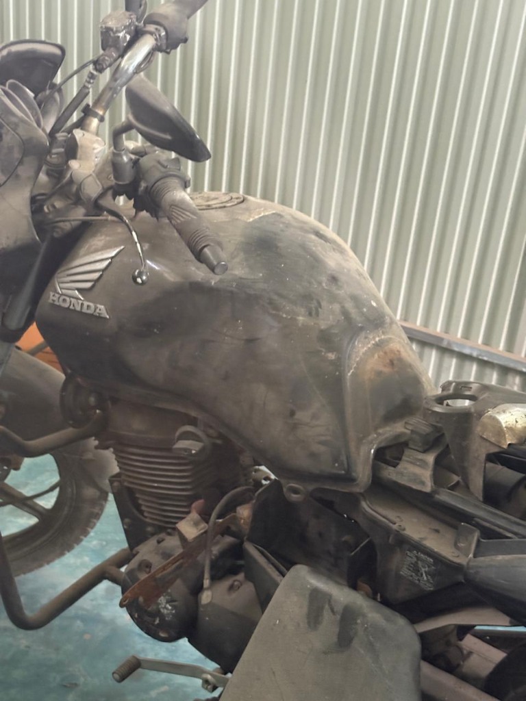 Disassembled black Honda commuter motorcycle prepared for restoration and engine rebuild in the service bay