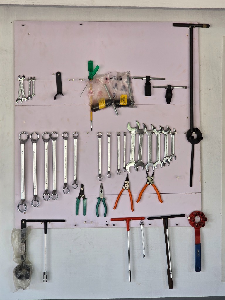 Organized pegboard with professional bike servicing wrenches, pliers, and specialized tools